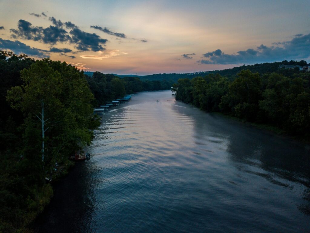 pexels-photo-1643702-1643702 Aerial view of a serene river with lush trees at sunrise, capturing nature's tranquility in Hollister, Missouri.