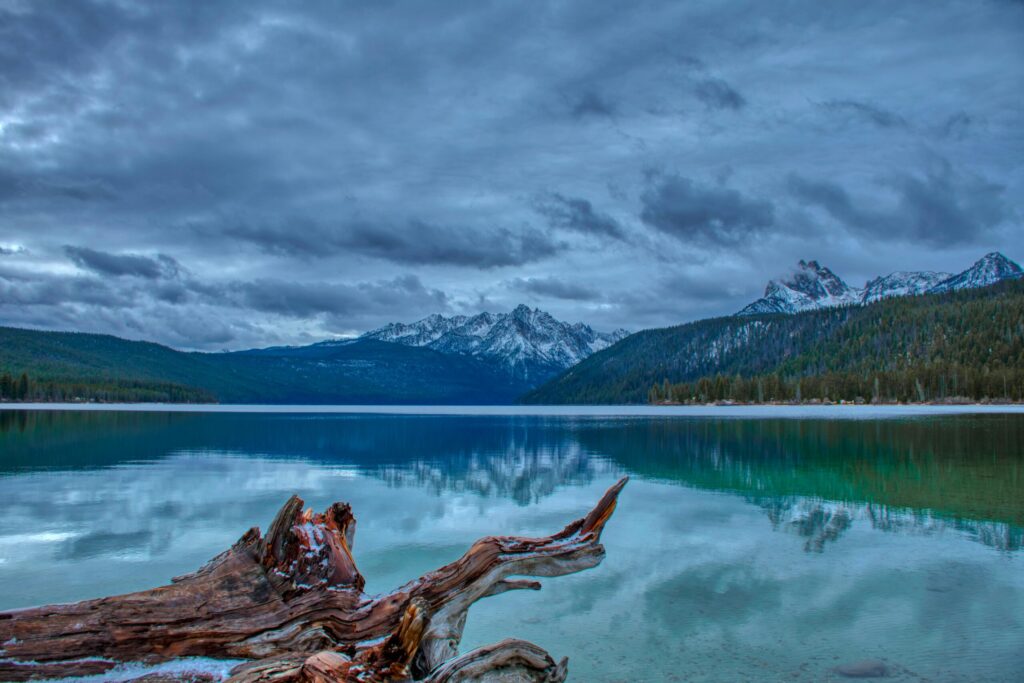A tranquil mountain lake with stunning reflections under dramatic cloudy skies.