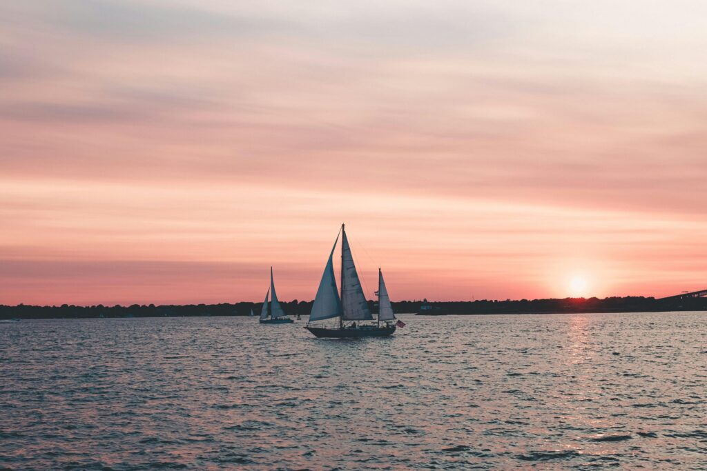 pexels-photo-2625752-2625752 Beautiful sunset view of sailboats gliding on the ocean with a vibrant sky.