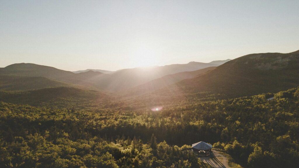 A breathtaking aerial view of a sunset over lush, rolling mountains in New Hampshire.