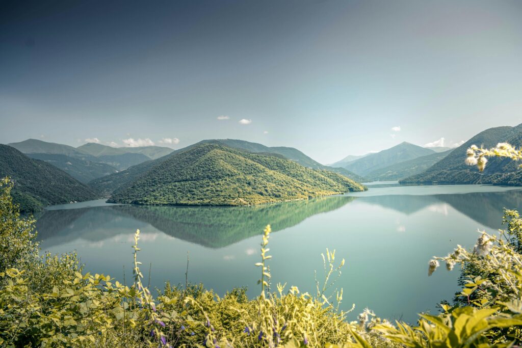 pexels-photo-2804123-2804123 Tranquil lake surrounded by lush green mountains under a clear summer sky.